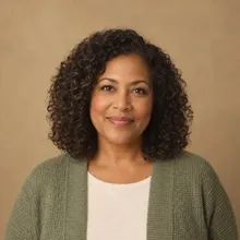 Portrait of Clara, a smiling woman with curly dark hair in a green cardigan